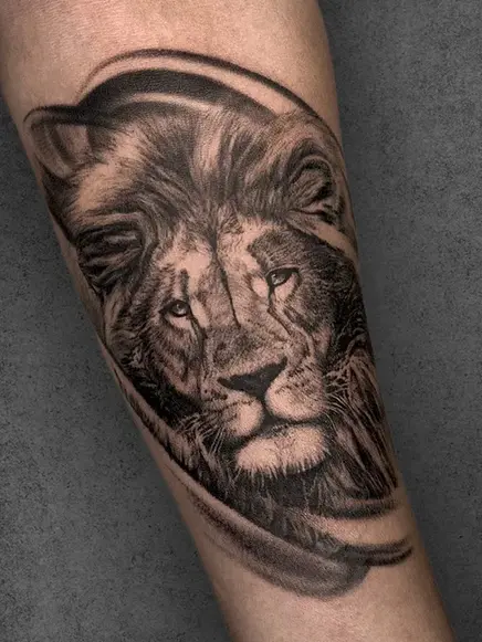 A fierce lion portrait with flowing mane, framed within curved abstract lines  | Realistic black and gray | Forearm | Male.