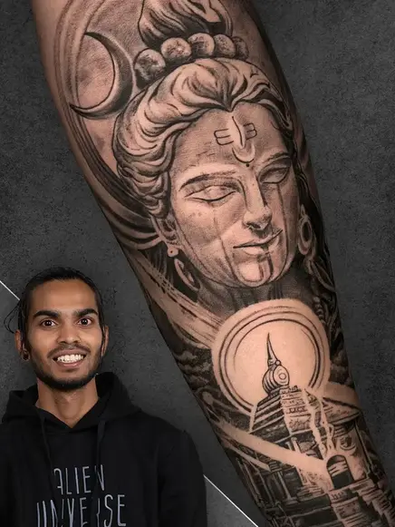 _Portrait of Tattoo Artist Harnam Bhagat with a tattoo depicting a serene Lord Shiva face with a crescent moon, on a male's forearm, in realistic black and grey shading style