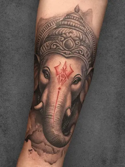 A highly detailed Ganesh tattoo with a red trishul and expressive eyes, enhancing the deity's divine presence