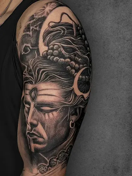 A powerful portrayal of Lord Shiva, this tattoo incorporates divine symbolism with bold shadows and intricate textures. The attention to detail in the facial features and jewelry highlights the reverence and strength associated with the deity.