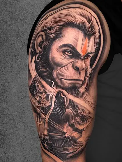 A powerful upper-arm tattoo of Lord Hanuman’s face, with a depiction of Lord Rama in the background