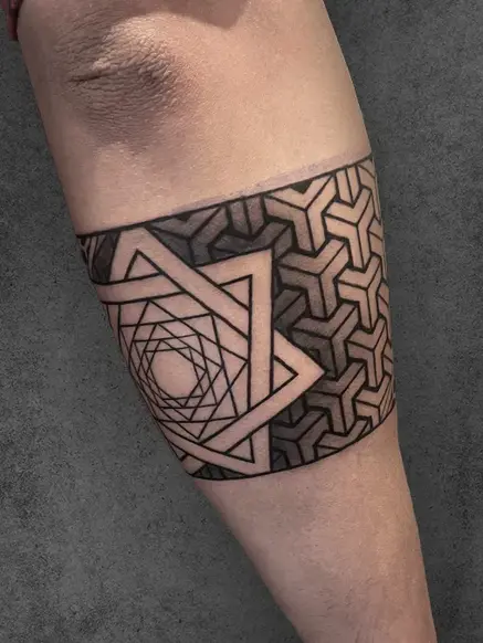 A geometric armband tattoo of an interwoven star encircled by a textured pattern, creating a bold statement on the arm