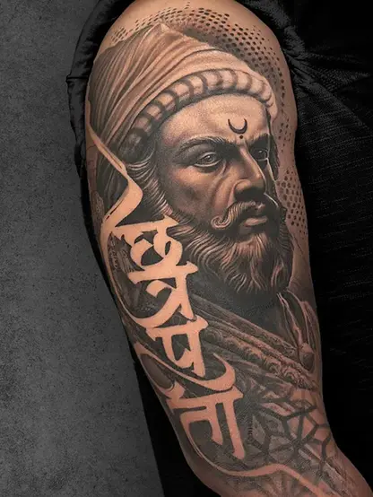Historical warrior portrait of Shivaji maharaj tattoo on male upper arm, black and grey realism with calligraphic script