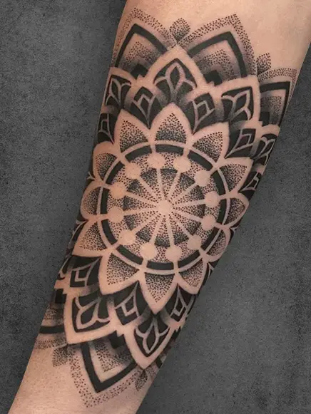  A large, ornate mandala tattoo covering the forearm, featuring symmetrical floral elements and dot work shading
