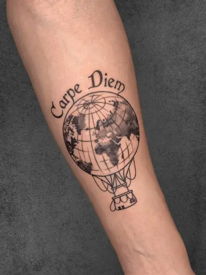 A tattoo of a globe incorporated into a hot air balloon with the text 'Carpe Diem,' symbolizing adventure and living in the moment, placed on the forearm