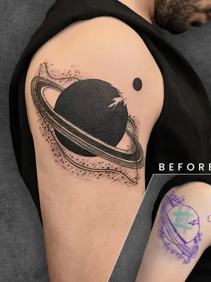 A vibrant black tattoo featuring Saturn, covering up a smaller tattoo that previously existed on the arm. The original tattoo is faint and unclear but visible in the bottom-left inset.