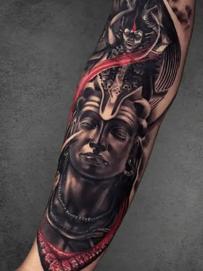 A mesmerizing tattoo of Lord Shiva’s serene face with vibrant red highlights, crowned with intricate skull details