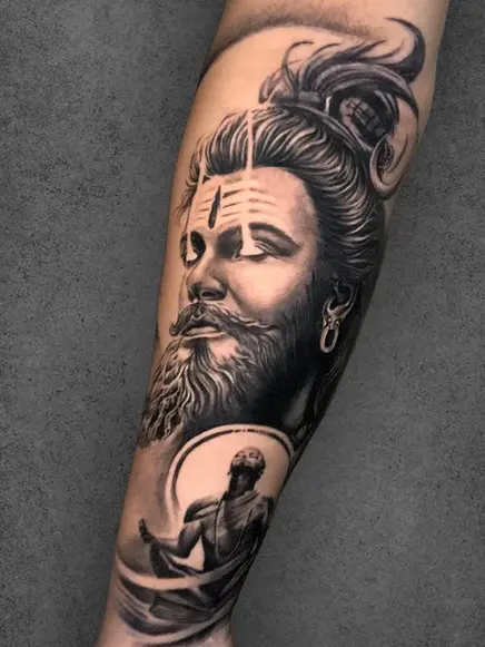 A Lord Shiva portrait tattoo on a male forearm with spiritual elements