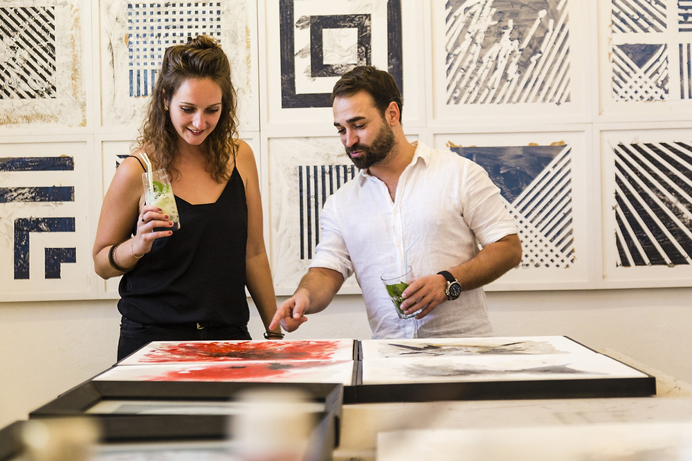 duas pessoas observando um quadro de arte, em Cuba.