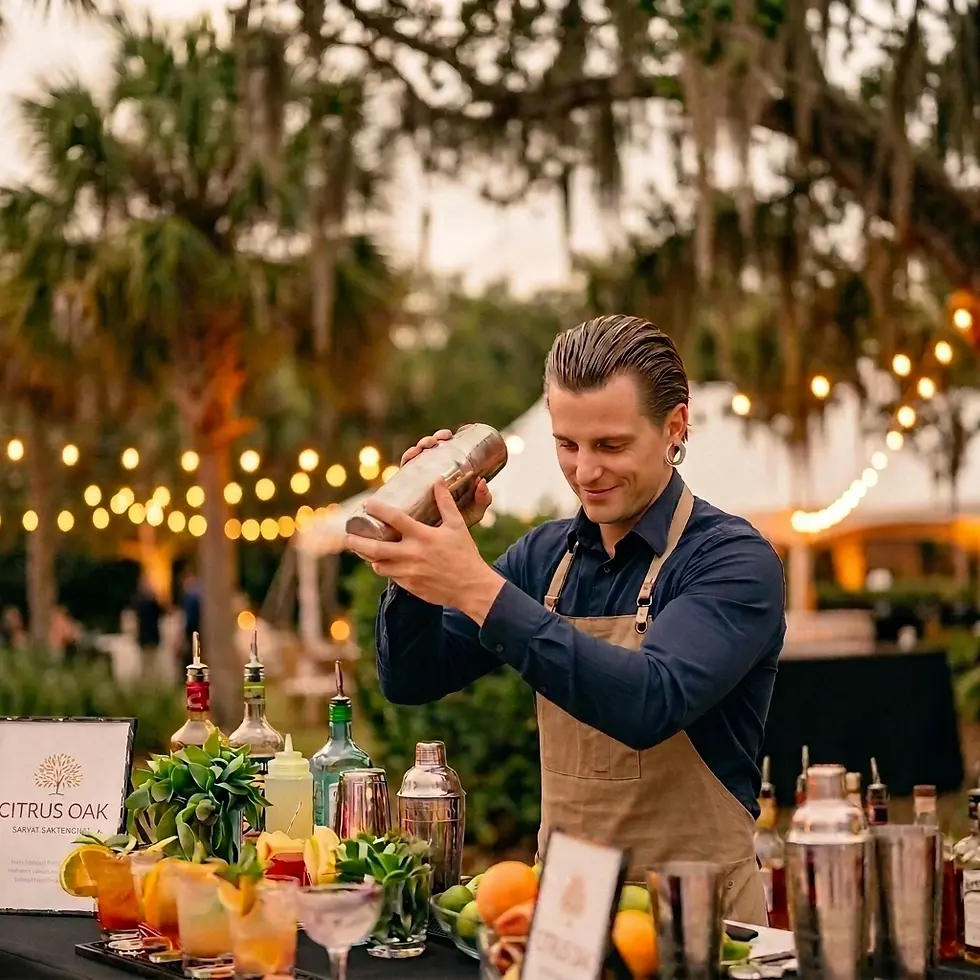 Event photography of a male bartender expertly shaking a cocktail shaker. He is preparing drinks at an outdoor event with ambient string lighting and a bar lined with colorful cocktails.