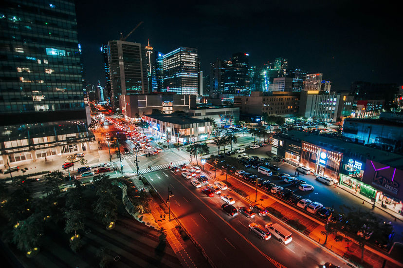 Busy nighttime cityscape with vehicle light trails and illuminated high‑rise buildings