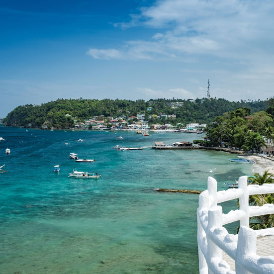 Coastal viewpoint overlooking clear blue water with boats and white railings