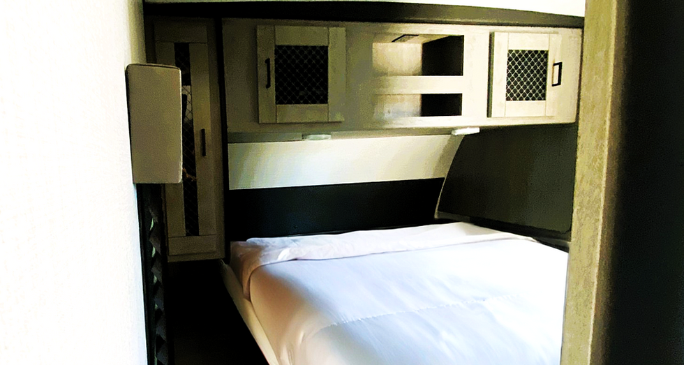 Queen bed in private bedroom area of trailer at Prado Park