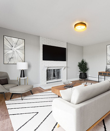 A spacious living room featuring a modern white sofa and a coffee table placed in the center, with a fireplace and a wall-mounted TV.