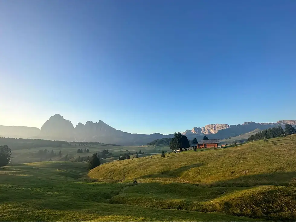 scenic view of a hilly landscape with mountains in the background under a clear blue sky