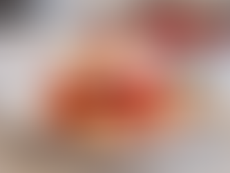 Strawberry shortcake with whipped cream and syrup on a plate, fork beside it, with a bowl of strawberries in the blurred background