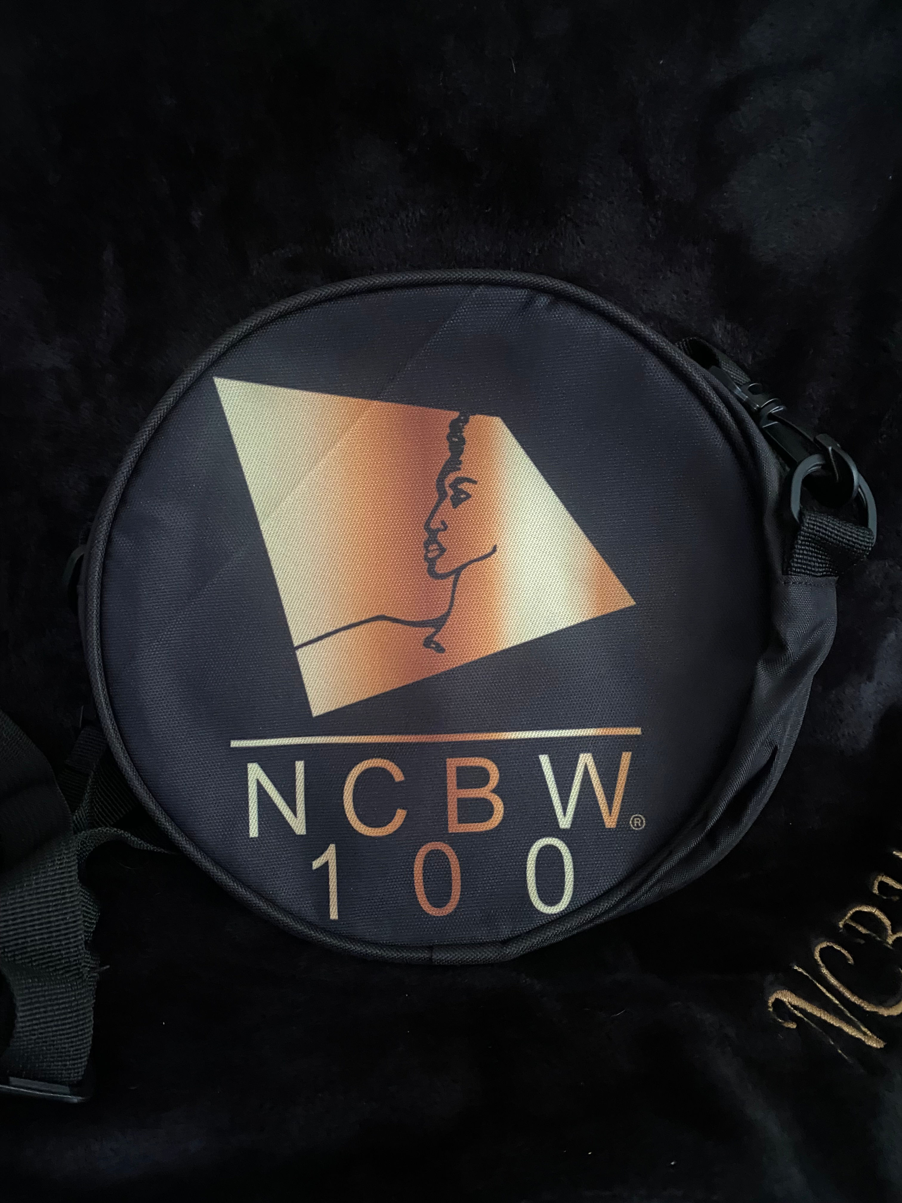 Round cross over the shoulder satchel bag with NCBW Logo