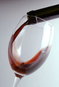 Weinglas, idem gerade mit Rotwein eingeschüttet  wird