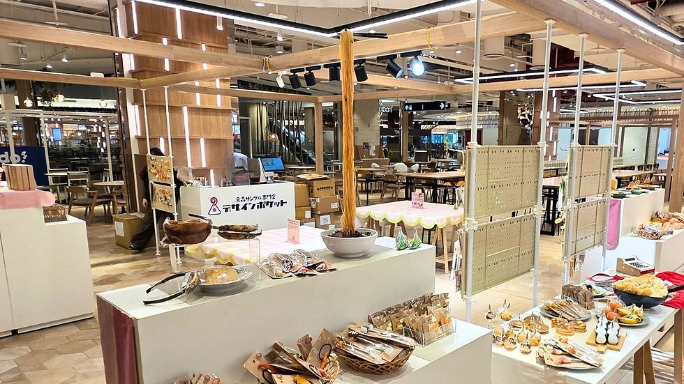 明るい商業施設内で、食品サンプル専門店デザインポケットの展示台にパンや菓子が並ぶ、空席の売り場。