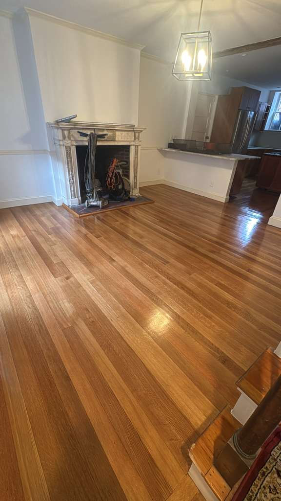 Room with polished wooden floor and fireplace.