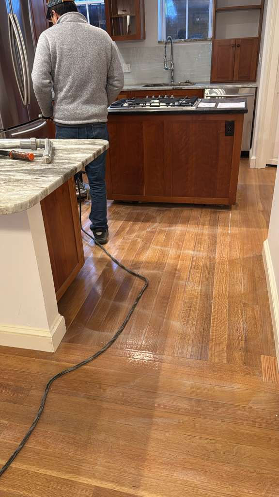 Person cleaning wooden floor with a machine.