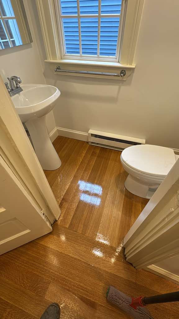 Small bathroom with wooden floor and white fixtures.