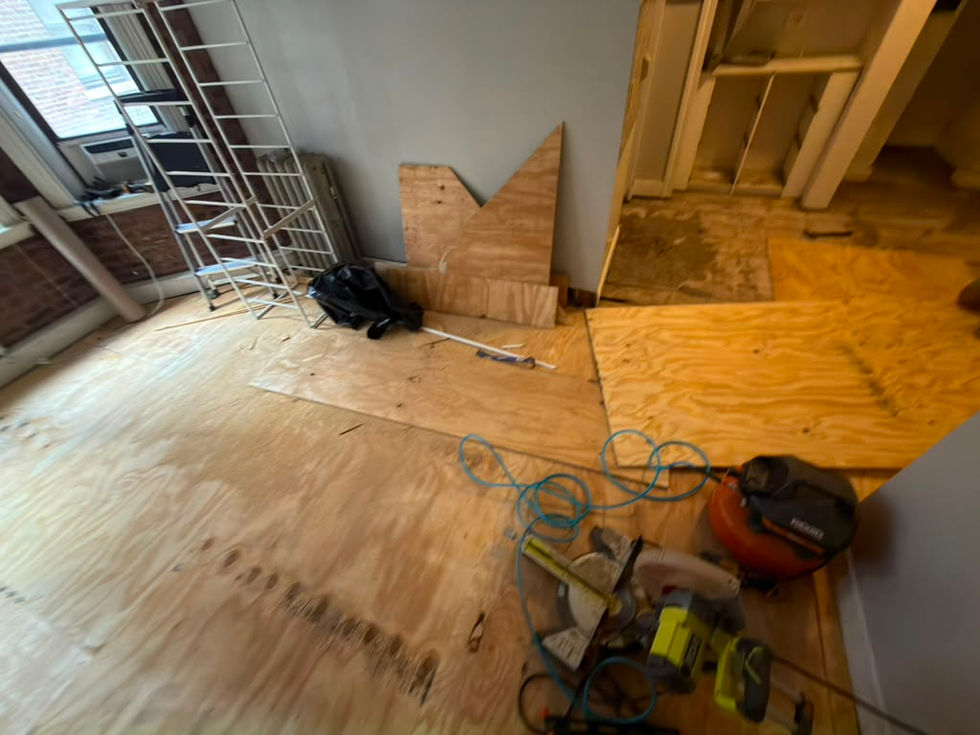 Room under renovation with tools and plywood flooring.
