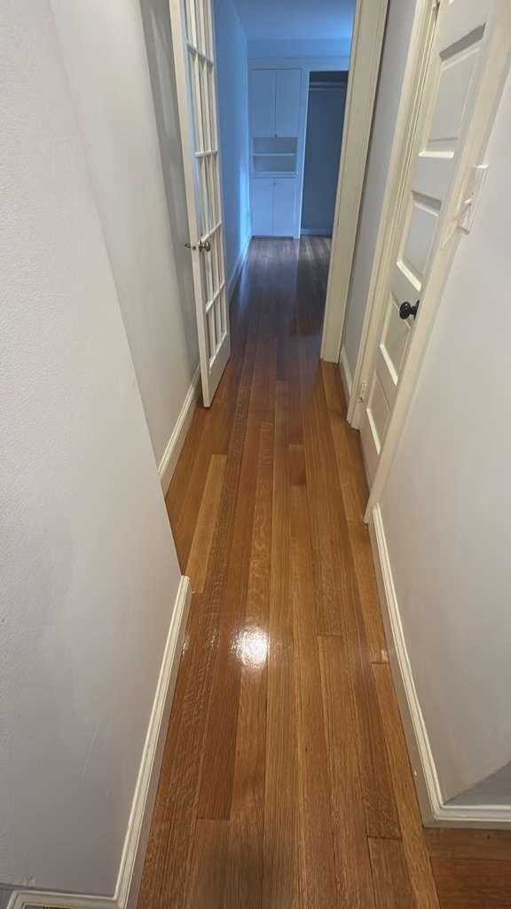 Shiny wooden hallway with white walls and doors.