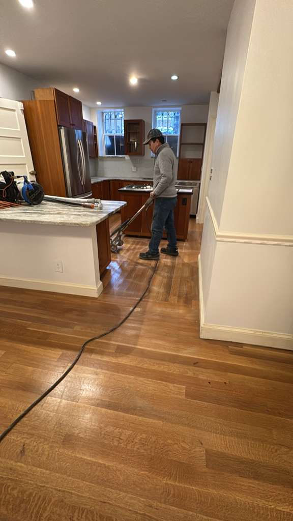 Person cleaning wooden floor in a kitchen area.
