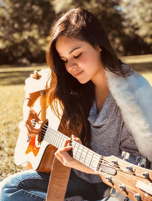 Teacher Mariana playing guitar, Kingwood Arts Academy, Houston TX.