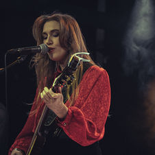 Emmy June singing and playing guitar live.