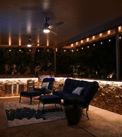 Luxury outdoor kitchen illuminated at night with built-in grill and seating area