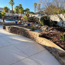 Stone veneer retaining wall paired with a curved patio.