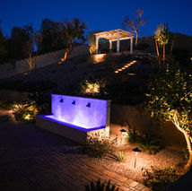 Backyard water feature illuminated by landscape lighting at night