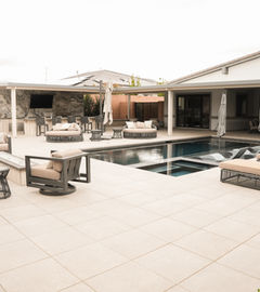 Outdoor patio with pool, seating, and LivingWaterLV. Pavers and Landscaping in a backyard setting.
