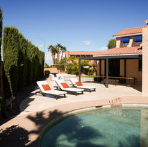 Patio with lounge chairs near pool and landscaping under blue sky