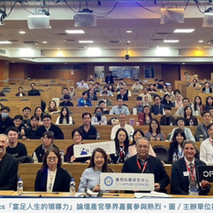 於階梯教室中的活動大合照，一些與會者拿著代表各學會領域的手卡和旗幟，例如應用科學研究中心、台灣女科技人學會、optica等