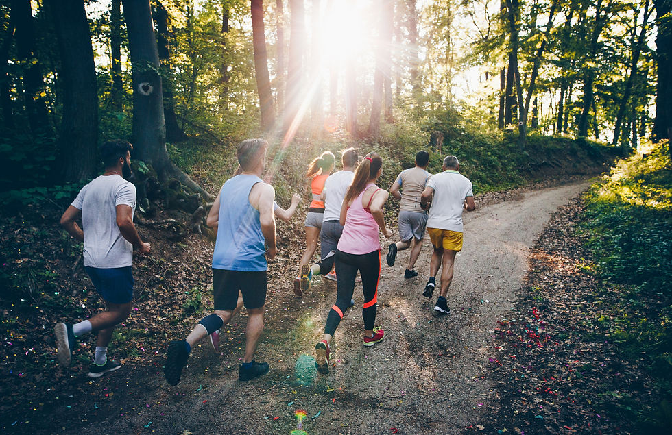 A group of runners jogging through a wooded path, with sunlight streaming through the trees.