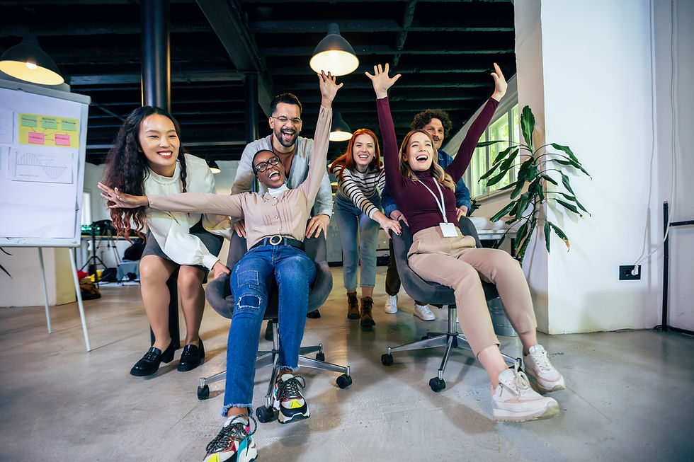 A team of coworkers enjoying a fun office chair race, with people pushing each other and cheering.