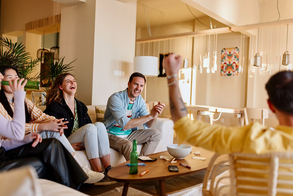 Group of friends laughing and celebrating together on a couch while playing a game in a living room.