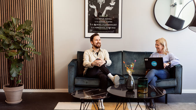 Smiling colleagues collaborating on a teal couch