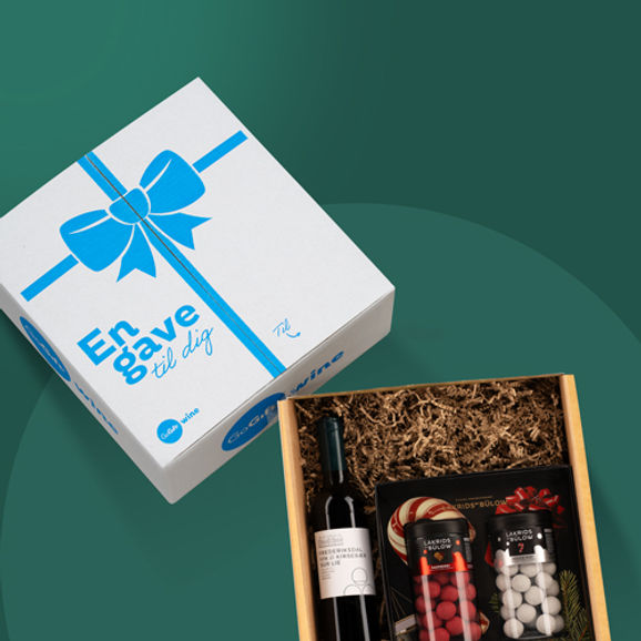 Gaveæske med vin og lakrids på grøn baggrund.