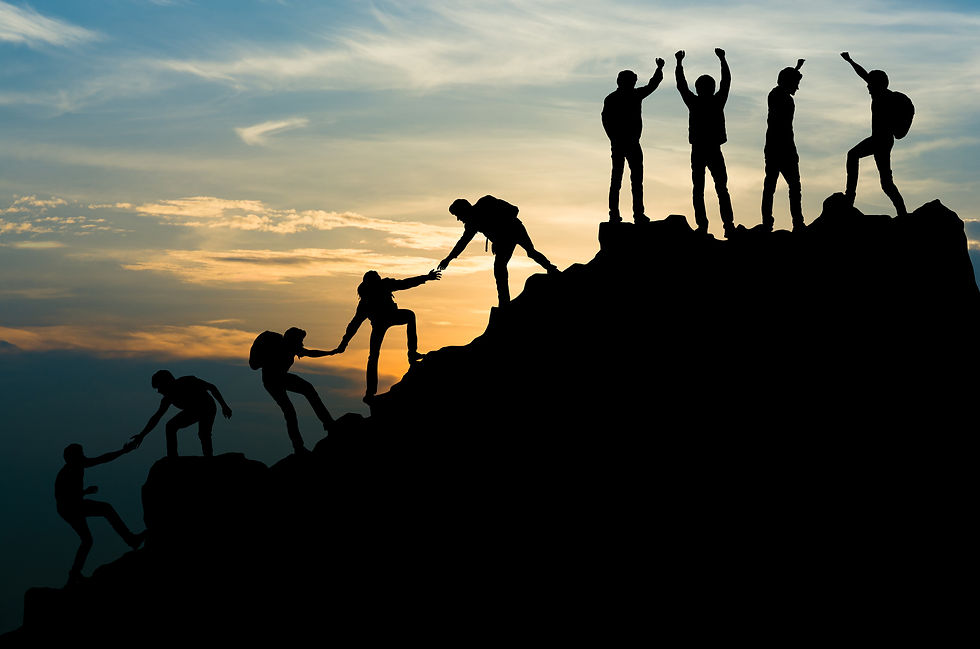 A group of mountain climbers helping each other reach the top and celebrating