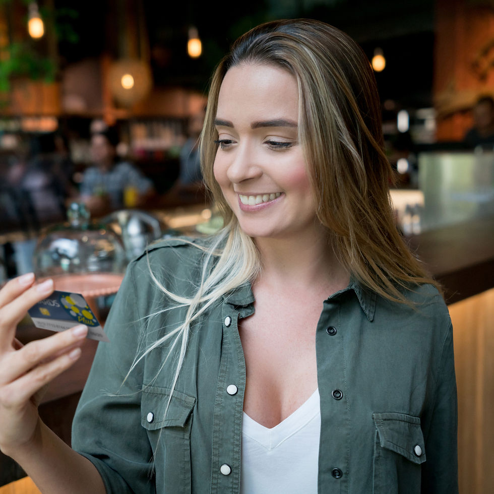 Smiling woman looking at a card in her hand while standing in a cafe.