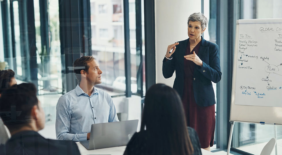 Businesswoman giving a presentation to a group in a conference room with a whiteboard.
