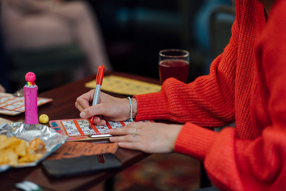 A person in a red sweater marking a bingo card with a red pen during a game.