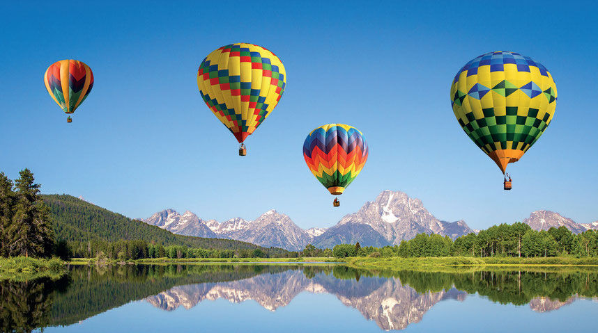 bunte-fesselballons-vor-sich-in-einem-see-wiederspiegelnden-alpenpanorama.jpg