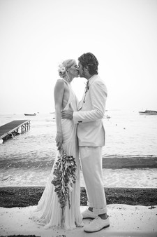 Black and white photo of newly weds kissing with the Amalfi Coast in the background