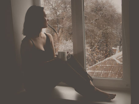 Woman sitting by a window with a cup of coffee during a quiet morning ritual
