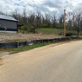 Installing silt fence for erosion control at construction site.